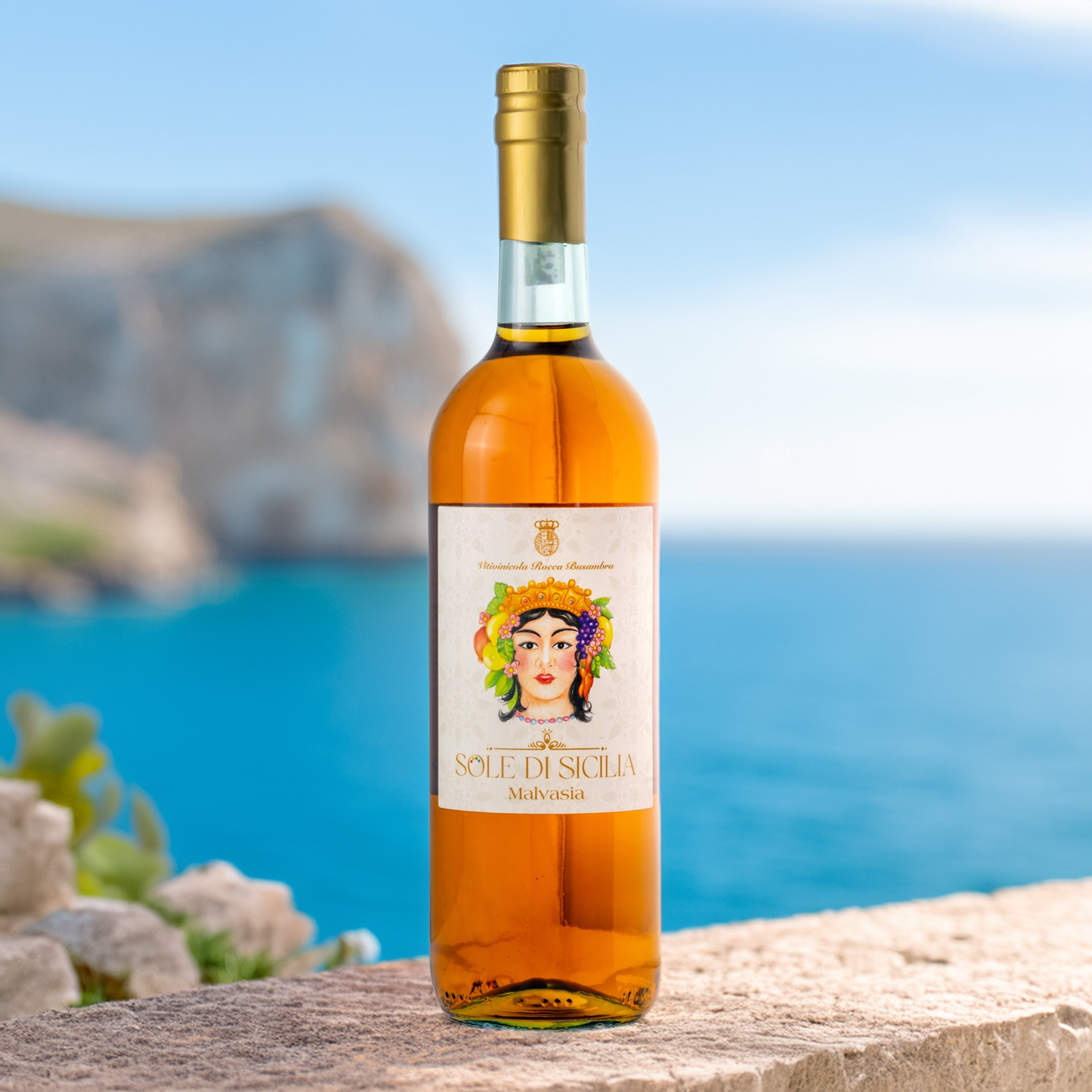 Flasche Sole di Sicilia Malvasia vor einer malerischen sizilianischen Küstenlandschaft mit Meer und Felsen – ein Likörwein aus Sizilien, perfekt zu Desserts und Süßspeisen. Erhältlich bei Nicoletti Feinkost.