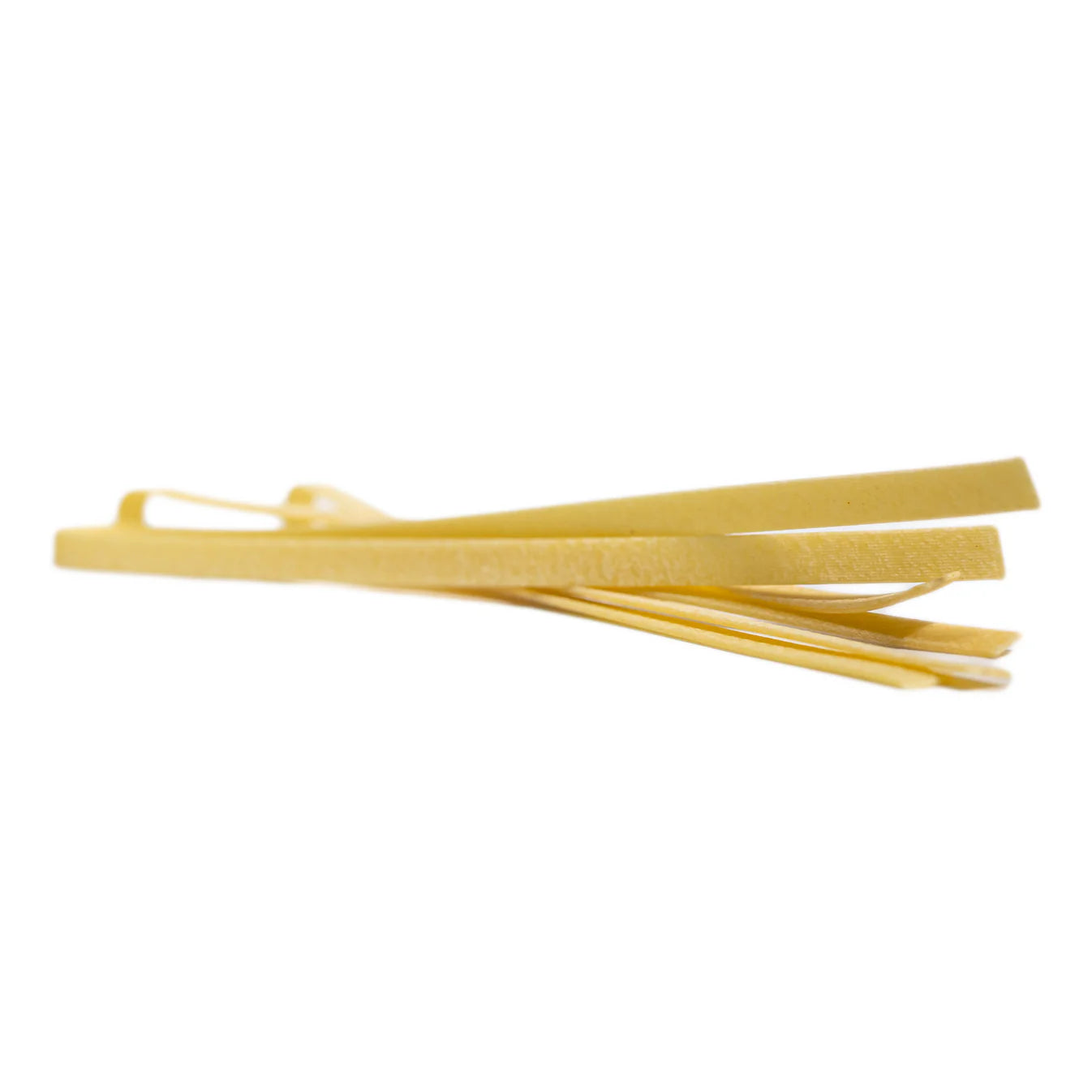 Tagliatelle Pasta Artigianale aus Sizilien – lose, liegend arrangiert, zeigt die raue Oberfläche und handwerkliche Verarbeitung.
